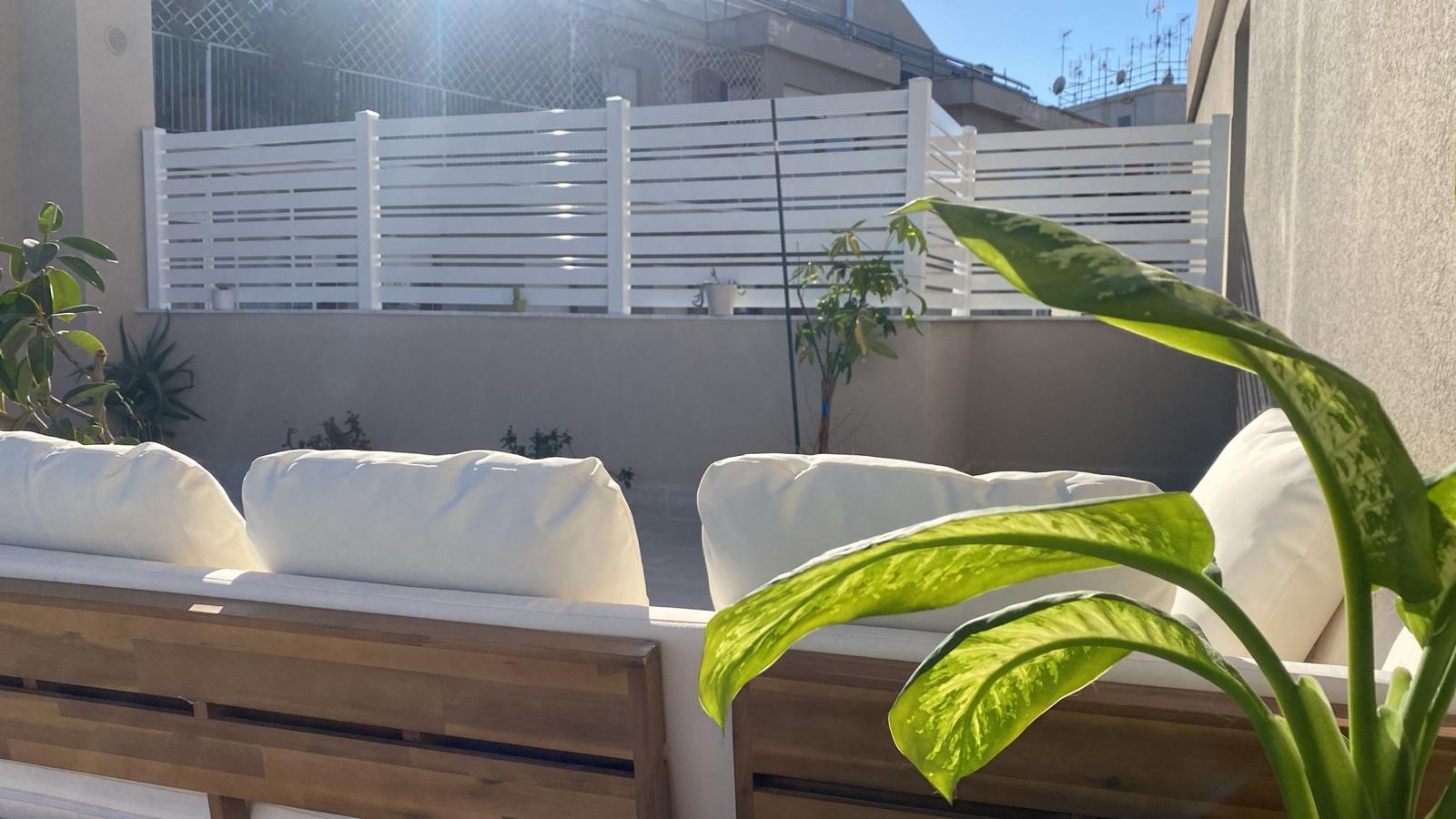 Frangivista in alluminio bianco a doghe orizzontali su terrazza con area relax