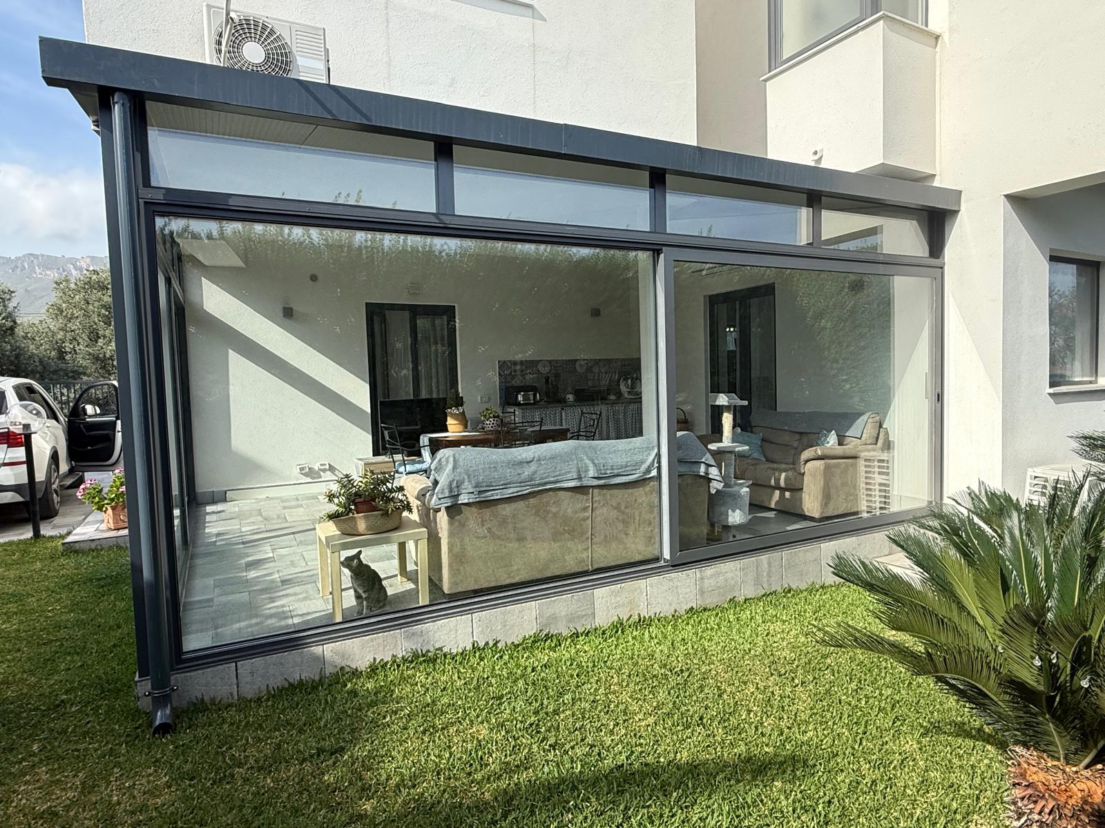 Veranda lineare in alluminio antracite con vetrate scorrevoli affacciata sul giardino