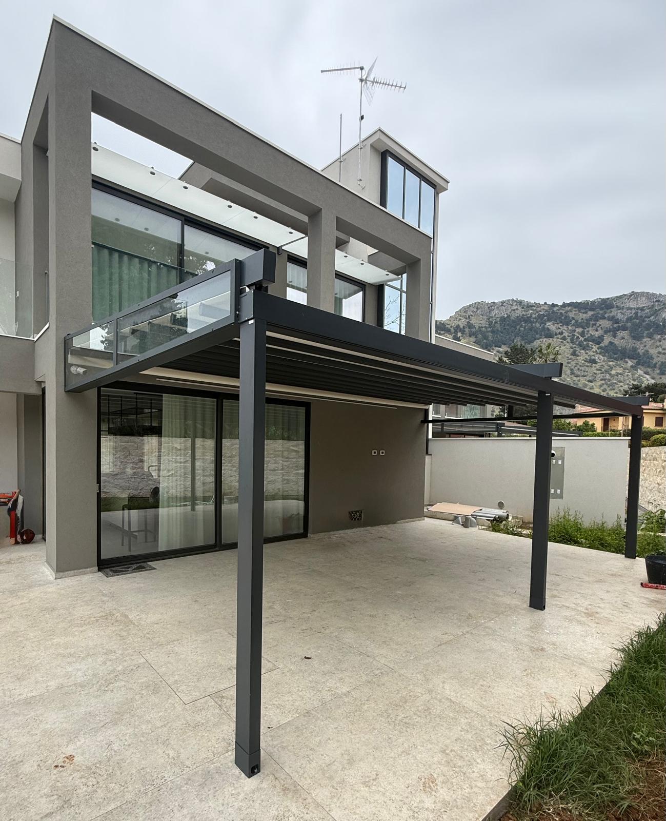Pergola bioclimatica antracite con lame orientabili addossata a villa moderna